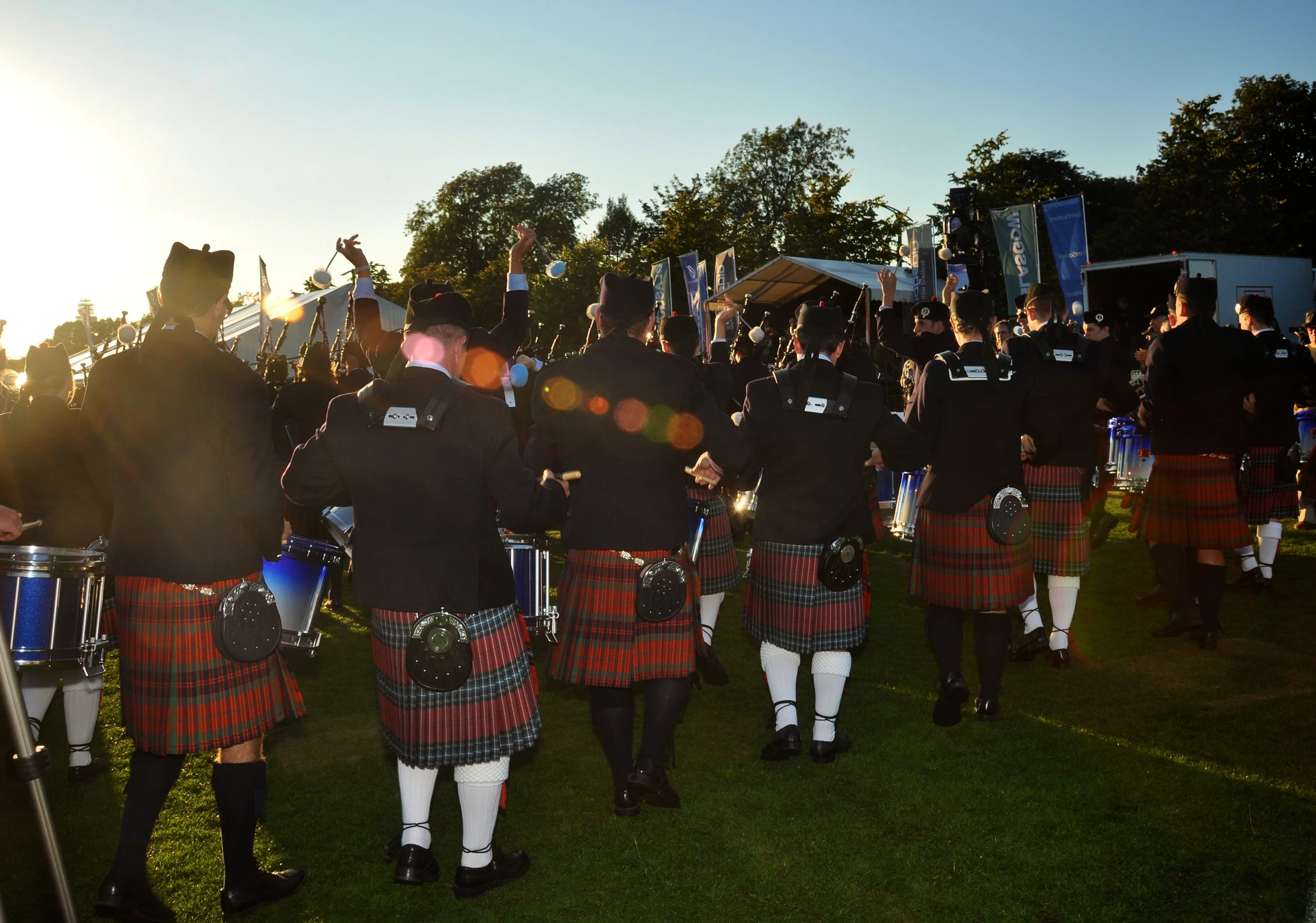 several scottish pipe players, some of whom are in kilts