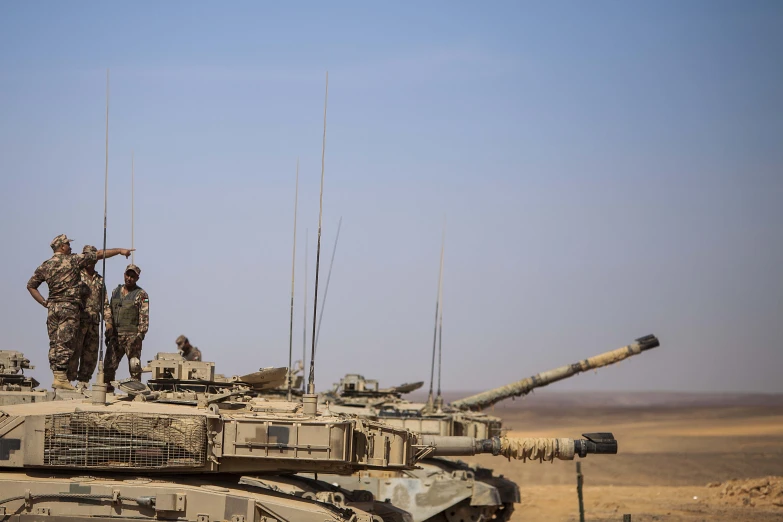 two men talking on top of tank next to it