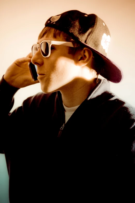 a young man talking on a cell phone in his hat