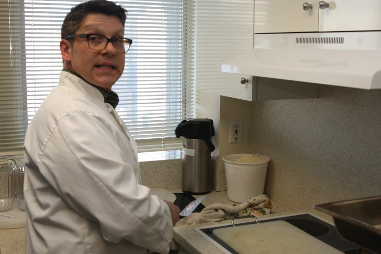 a person in glasses stands near a counter