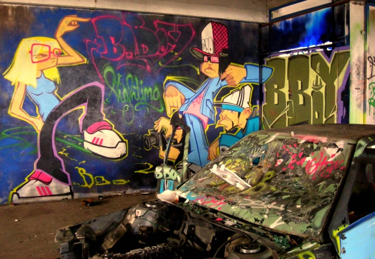 a wrecked car sitting in front of some graffiti covered walls