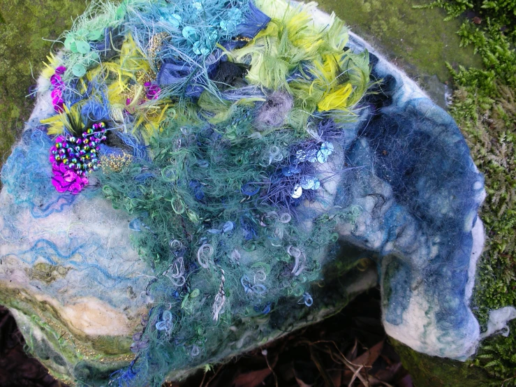 a piece of multi colored material sitting on top of a green grass covered ground