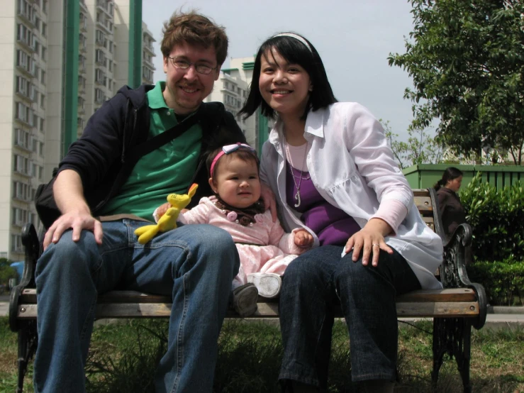 there is a male sitting next to a woman holding a baby and a girl in front of him