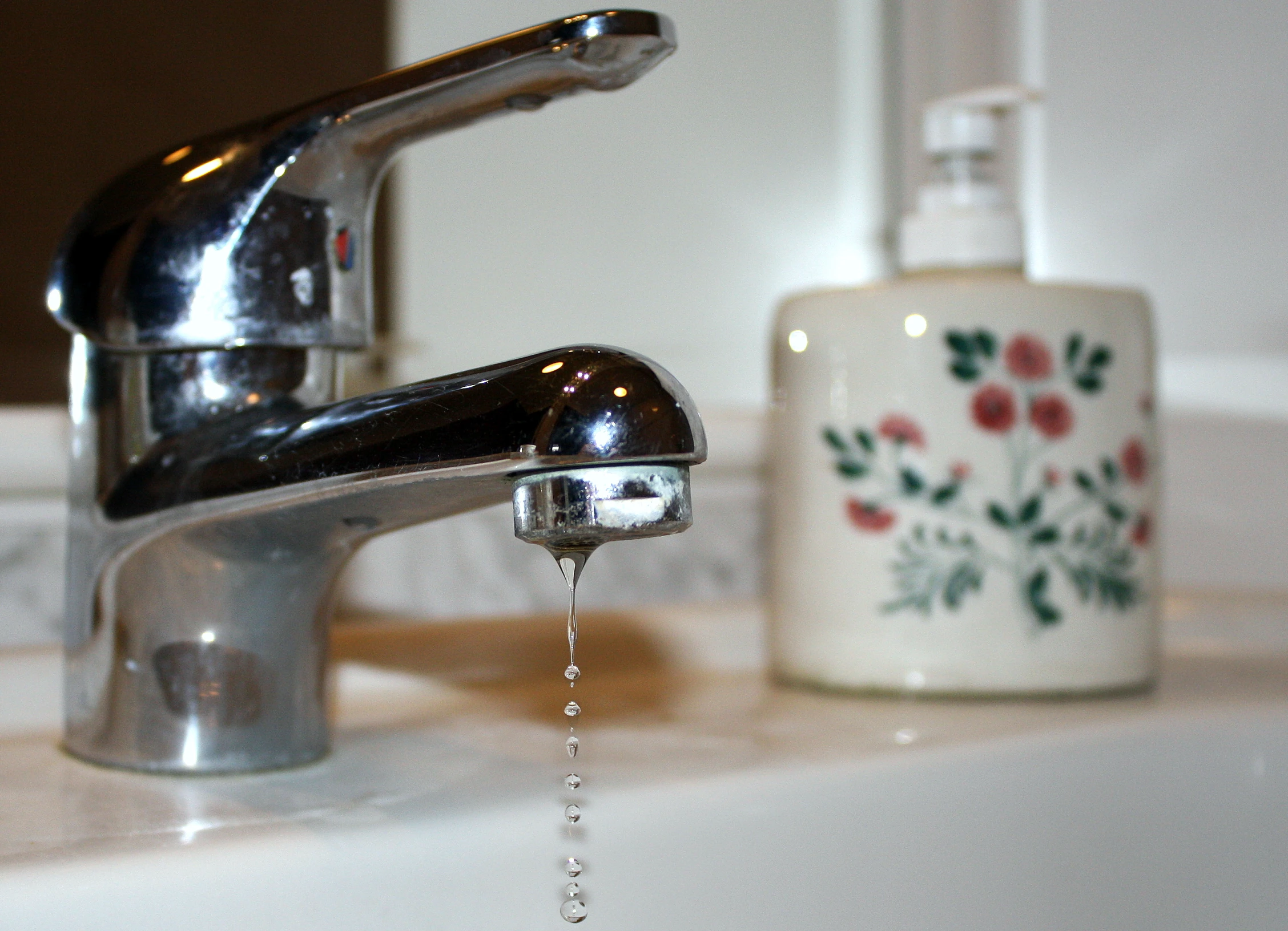 a faucet with soap and water in it next to a cup of wash