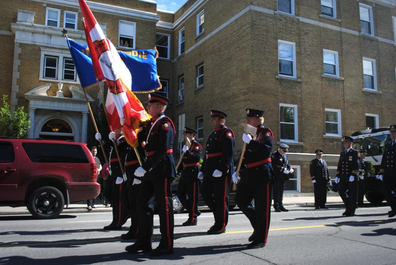 some men in uniforms are marching and holding flags