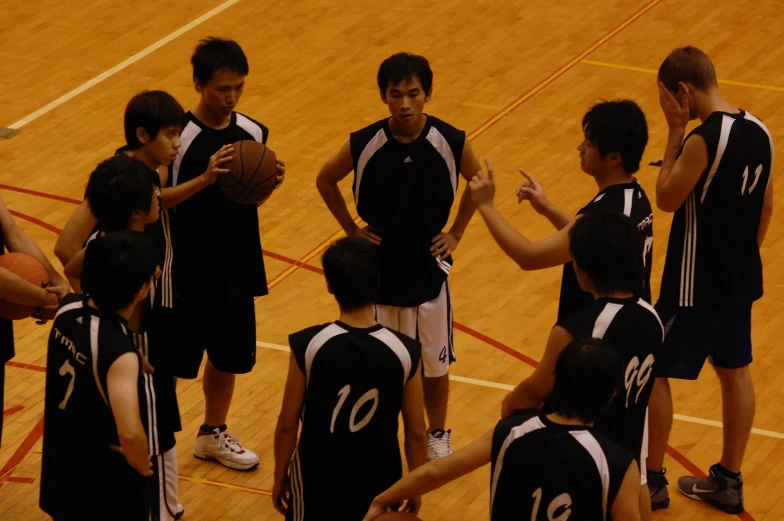 a group of young men holding hands over the basketball during a game