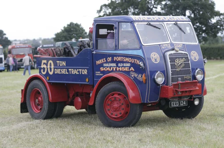 a blue and red truck with white writing parked in the grass