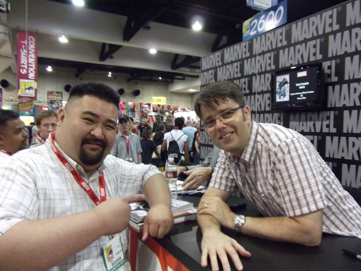 two men posing for a picture while they are at a booth