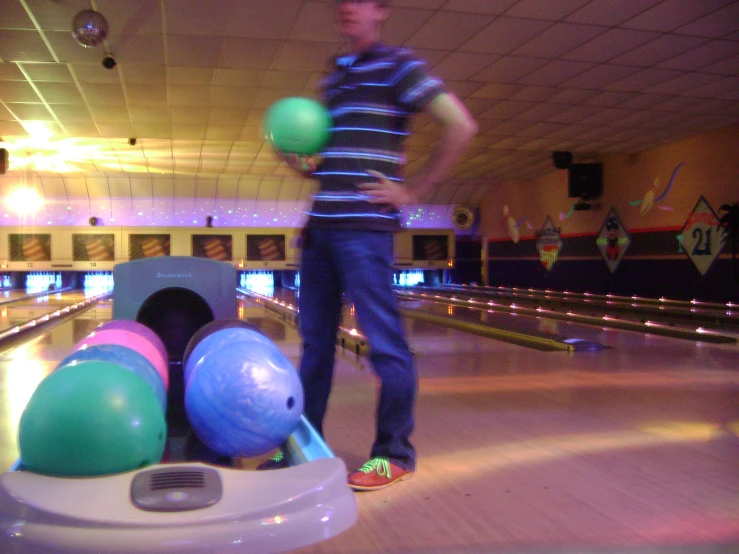 a man on the bowling alley throwing three balls