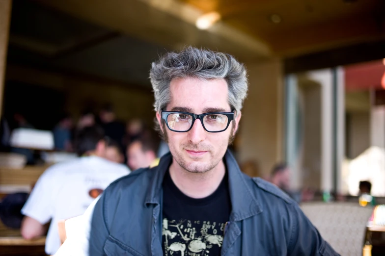 a man wearing glasses looking at the camera in a restaurant