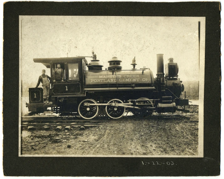 an old train with men standing on top and a car attached to it