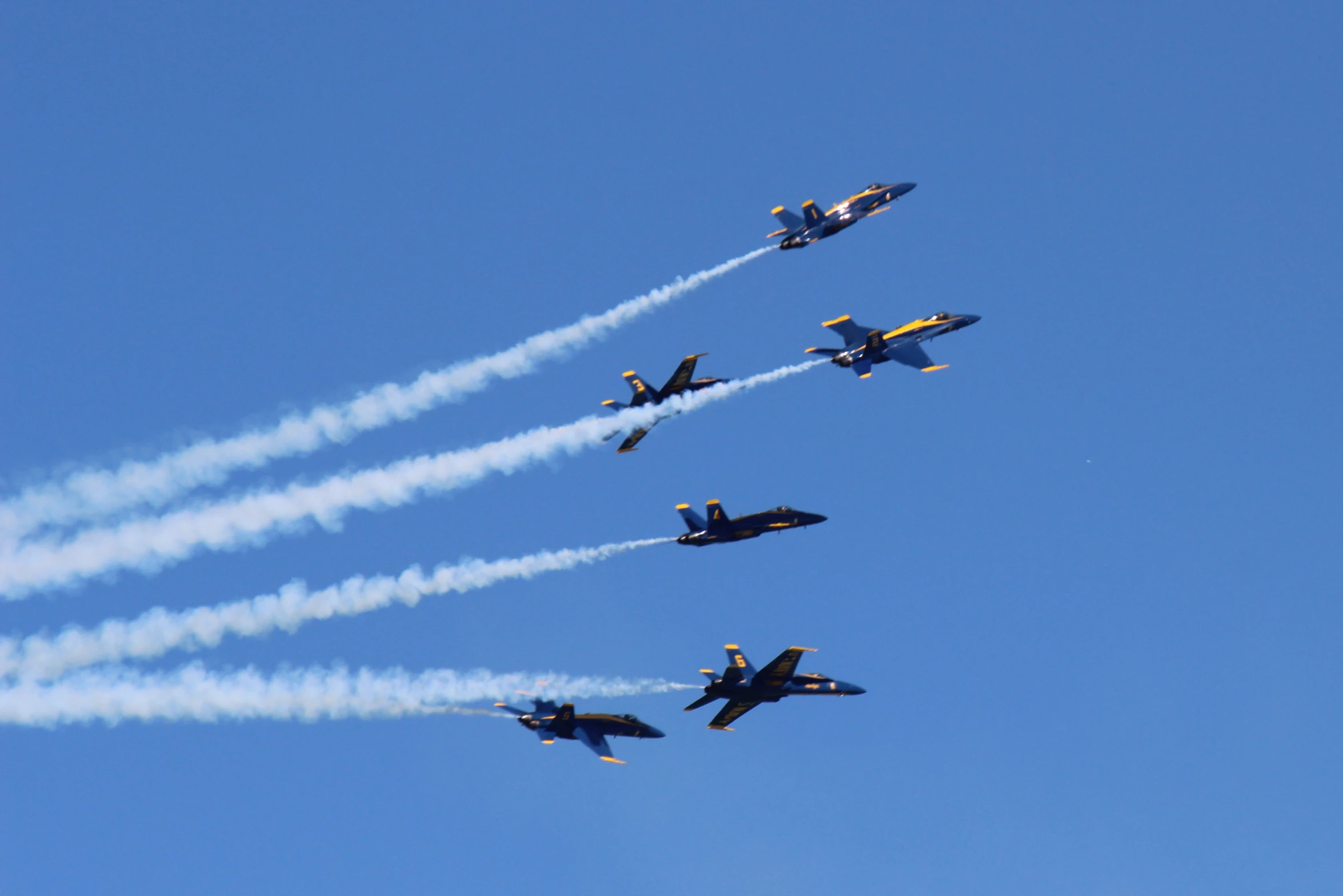 a group of planes flying in formation under blue skies