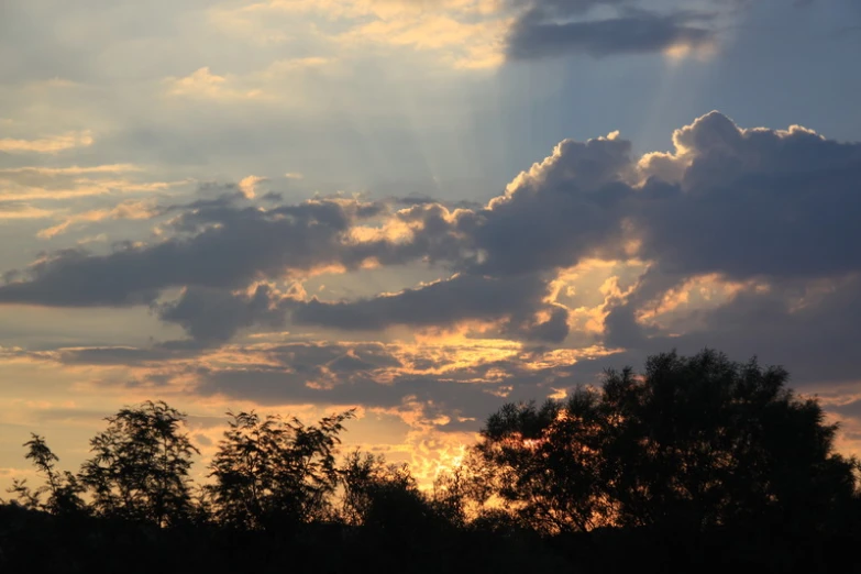 the sun shining through clouds as it goes down