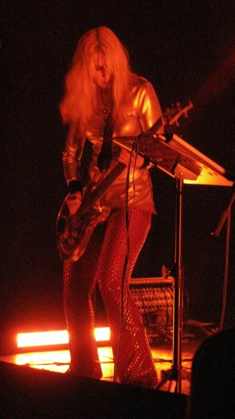 a woman with a guitar stands by a microphone