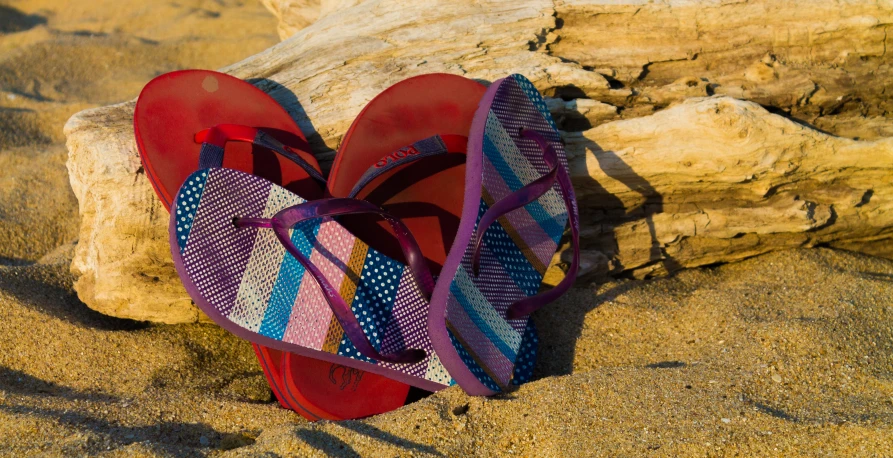 two sandals on the sand with one laying on the ground