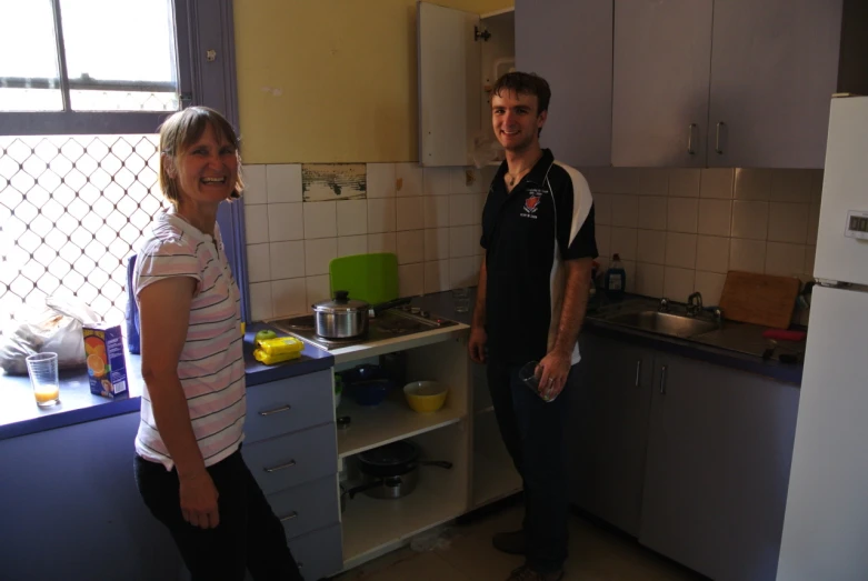 a man and woman standing in the kitchen near the sink