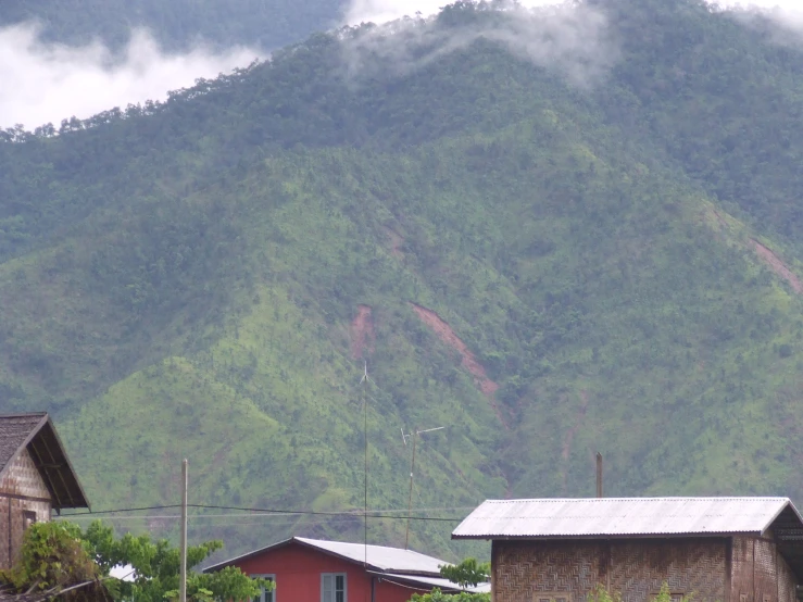 mountains with grass and clouds near houses