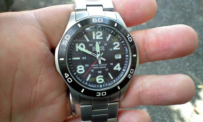 a black and grey watch being held in a man's hand