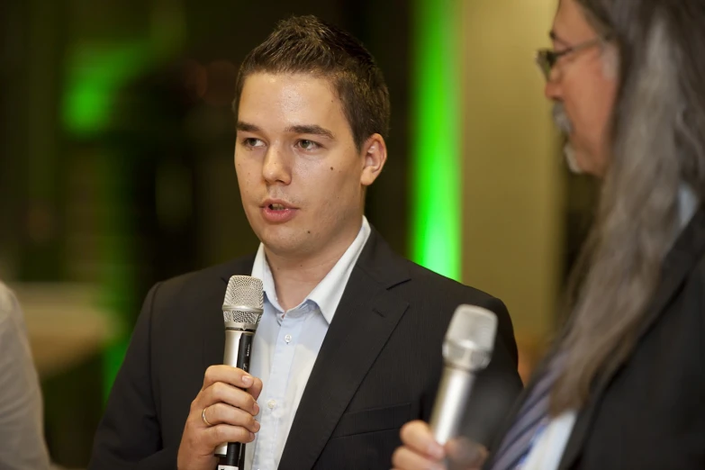 a young man talking into a microphone next to a woman