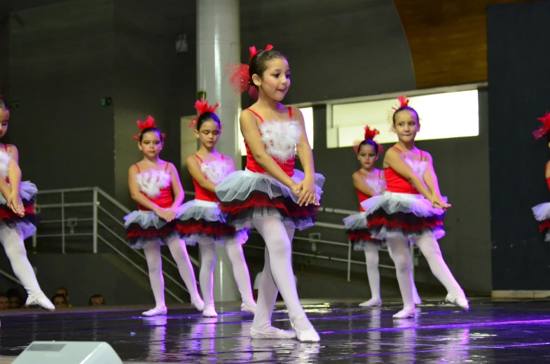 a group of children dressed in red, pink and white doing different moves