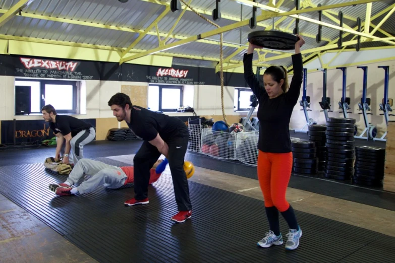 three people are doing exercises in a gym