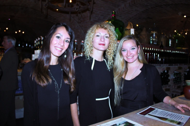 three beautiful young women standing in front of a menu