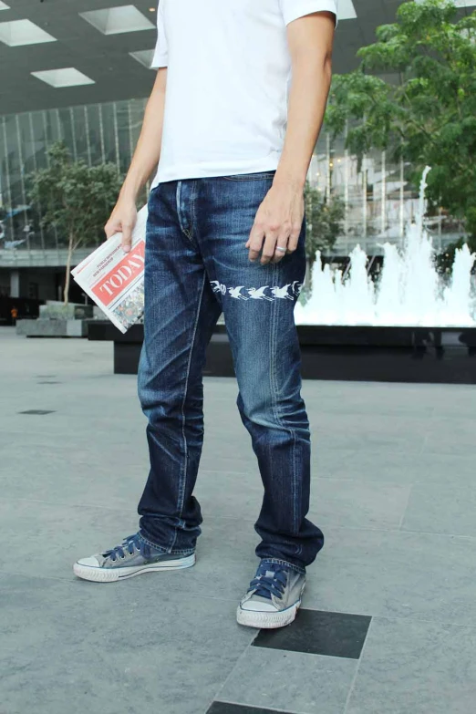 man standing in a lobby, wearing dark jeans and white tee shirt