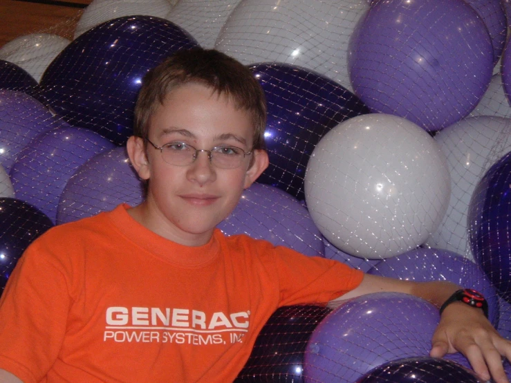 a boy sitting in the middle of a bunch of balloons