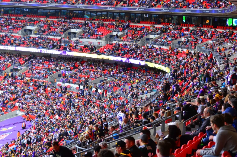 a large stadium with people, one person is standing on the sidelines and several are sitting down