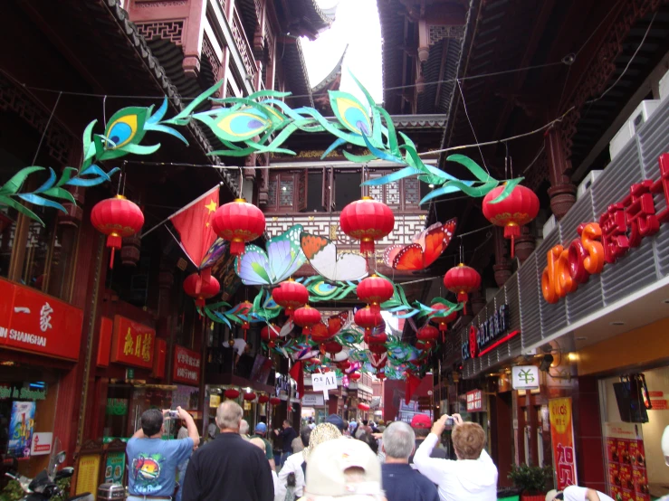 many people walking down a busy street under lanterns