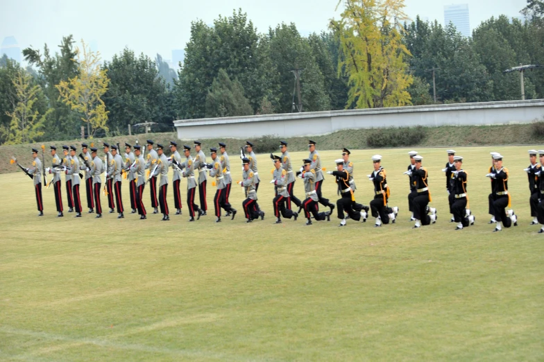 a line of men standing next to each other on top of a lush green field