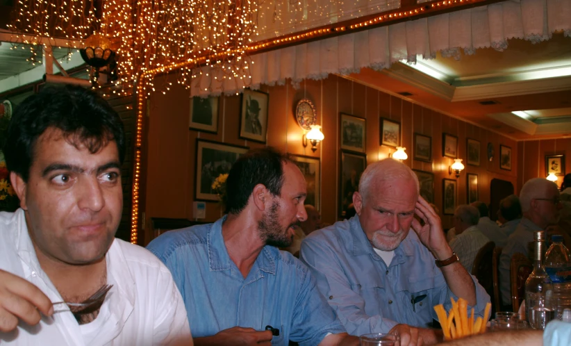 men seated at a table with plates and food