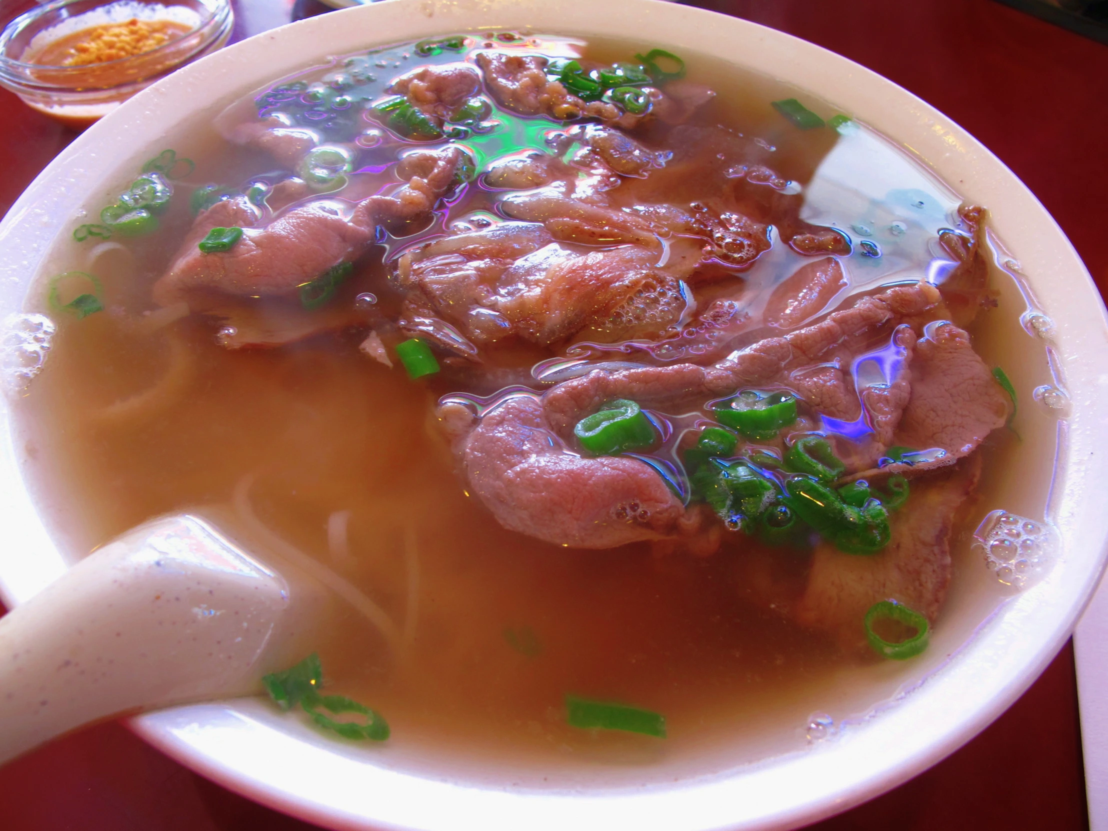 a white bowl filled with soup and meat in broth