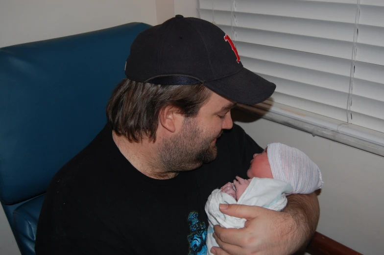 a man wearing a black cap and holding a white baby