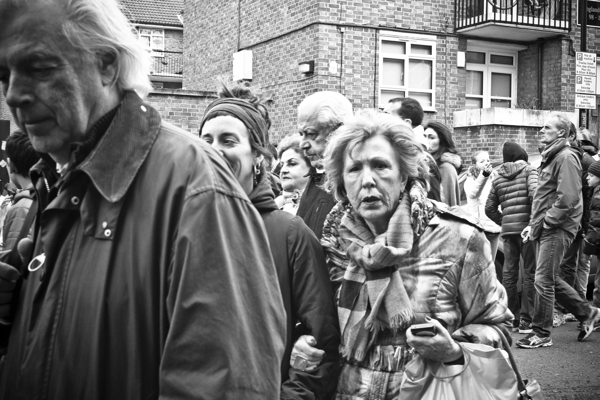 a crowd of people in various ages are standing on the street