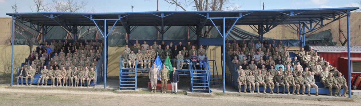 a building with a blue frame, a bunch of people in camo standing and leaning against it