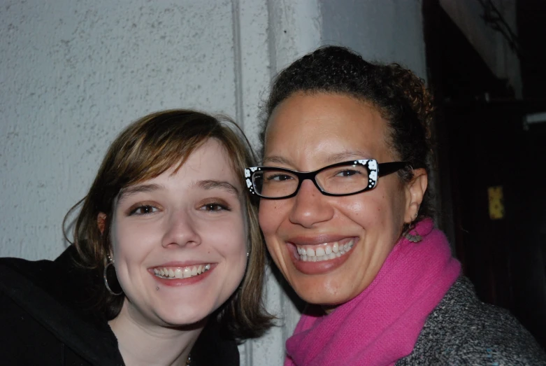 two women smiling at the camera with a white door in the background