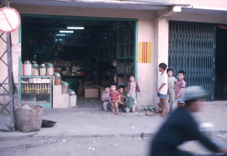 a couple of children in front of a store with their mother