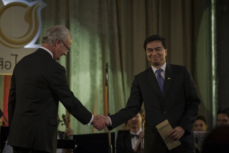 two men are shaking hands in front of an audience