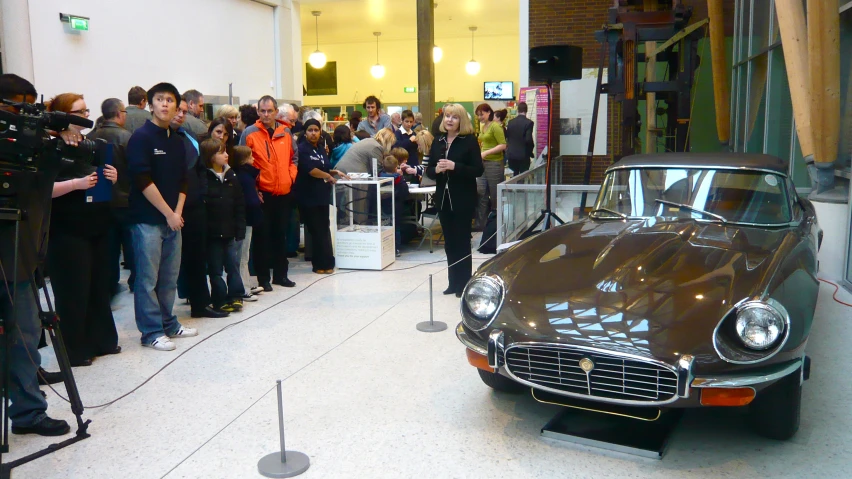 old - time cars being watched by cameras at an event