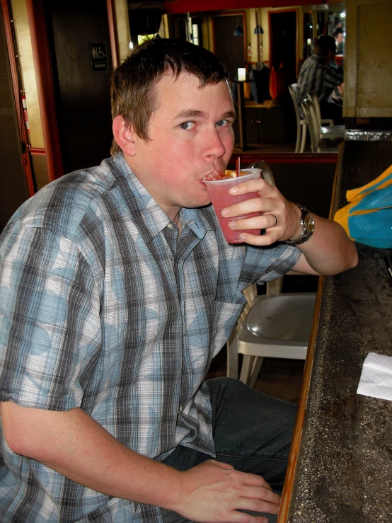 the man is sipping a drink from a glass