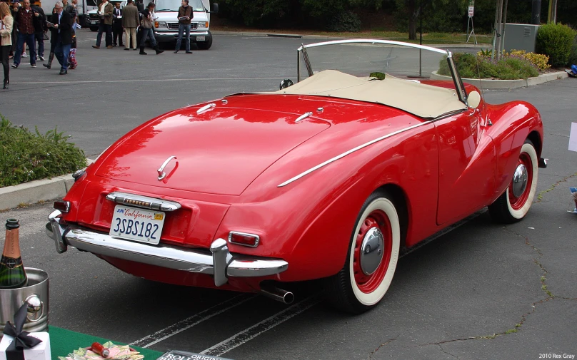 an older, red car is parked in a parking lot