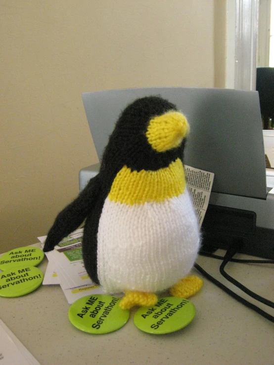 a stuffed penguin is posed on the wall by the computer