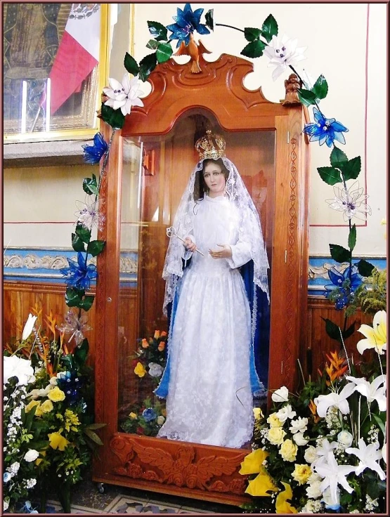 a religious statue with flowers around the frame