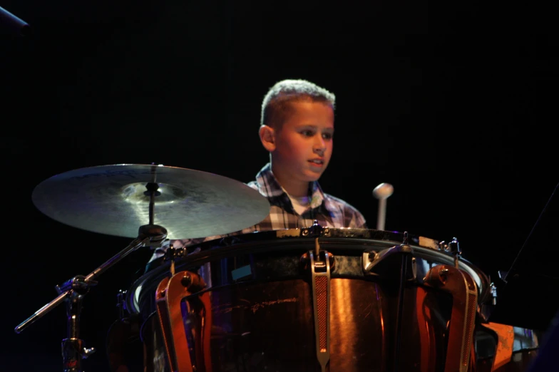 a child playing drums with sticks behind it