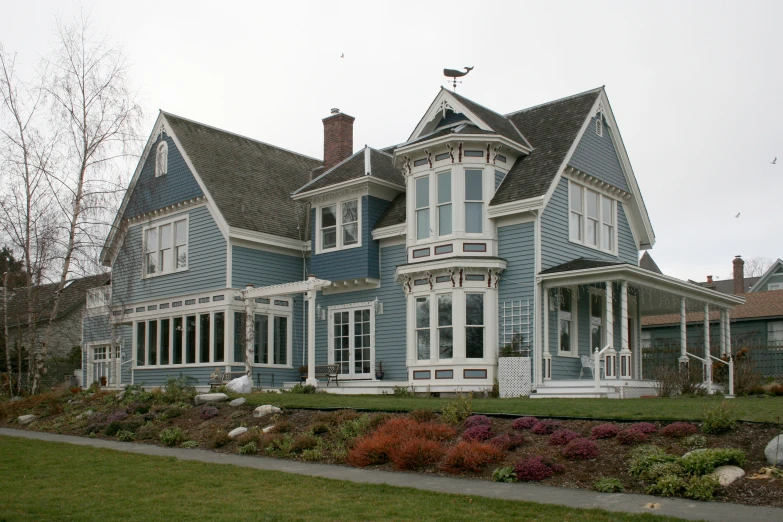 a blue two story house with a porch and large windows