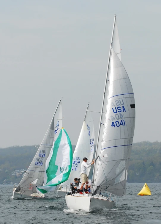 a group of three sailboats with a person on the front in the water