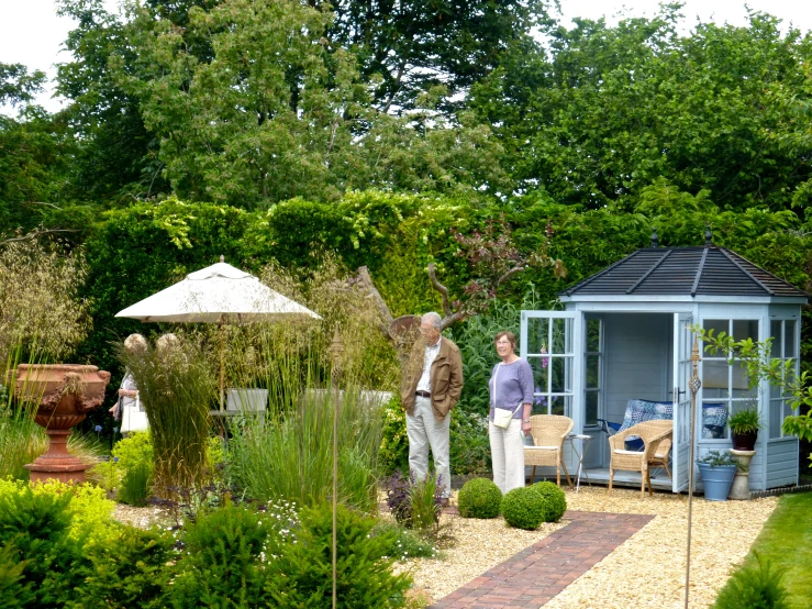 two men are standing in the garden next to a gazebo