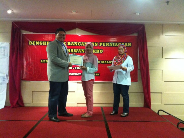 people in a room near some red curtains with a ribbon