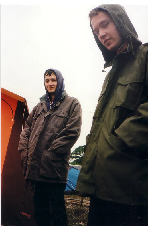 two men standing next to each other wearing jackets